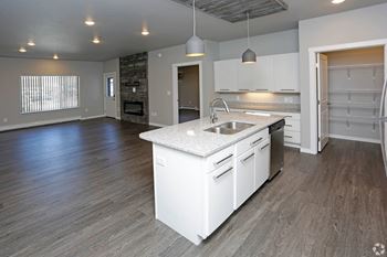 A kitchen with white cabinets and a white island with a stainless steel sink